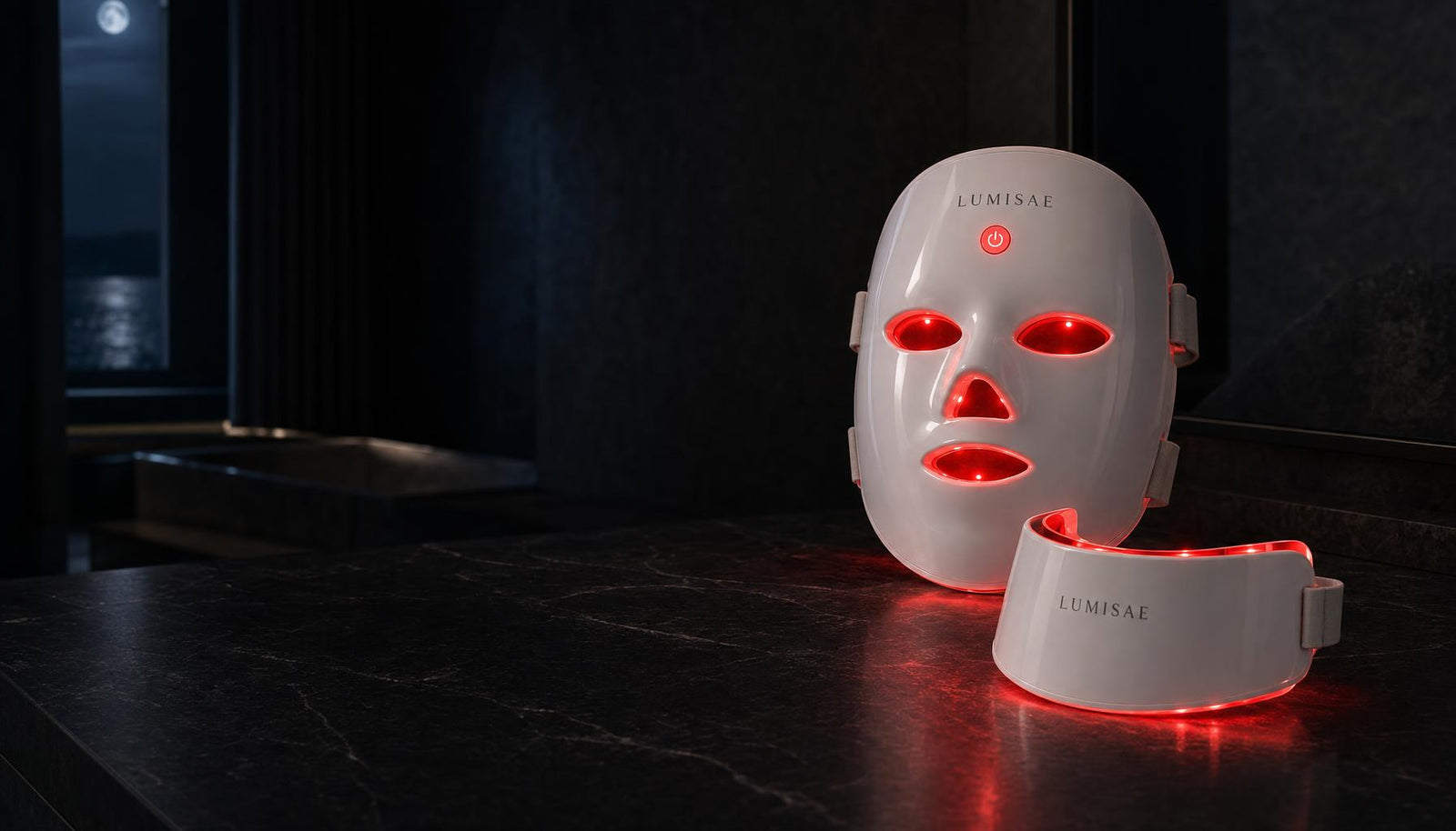 Lumisae LED mask and neck piece glowing red on dark marble