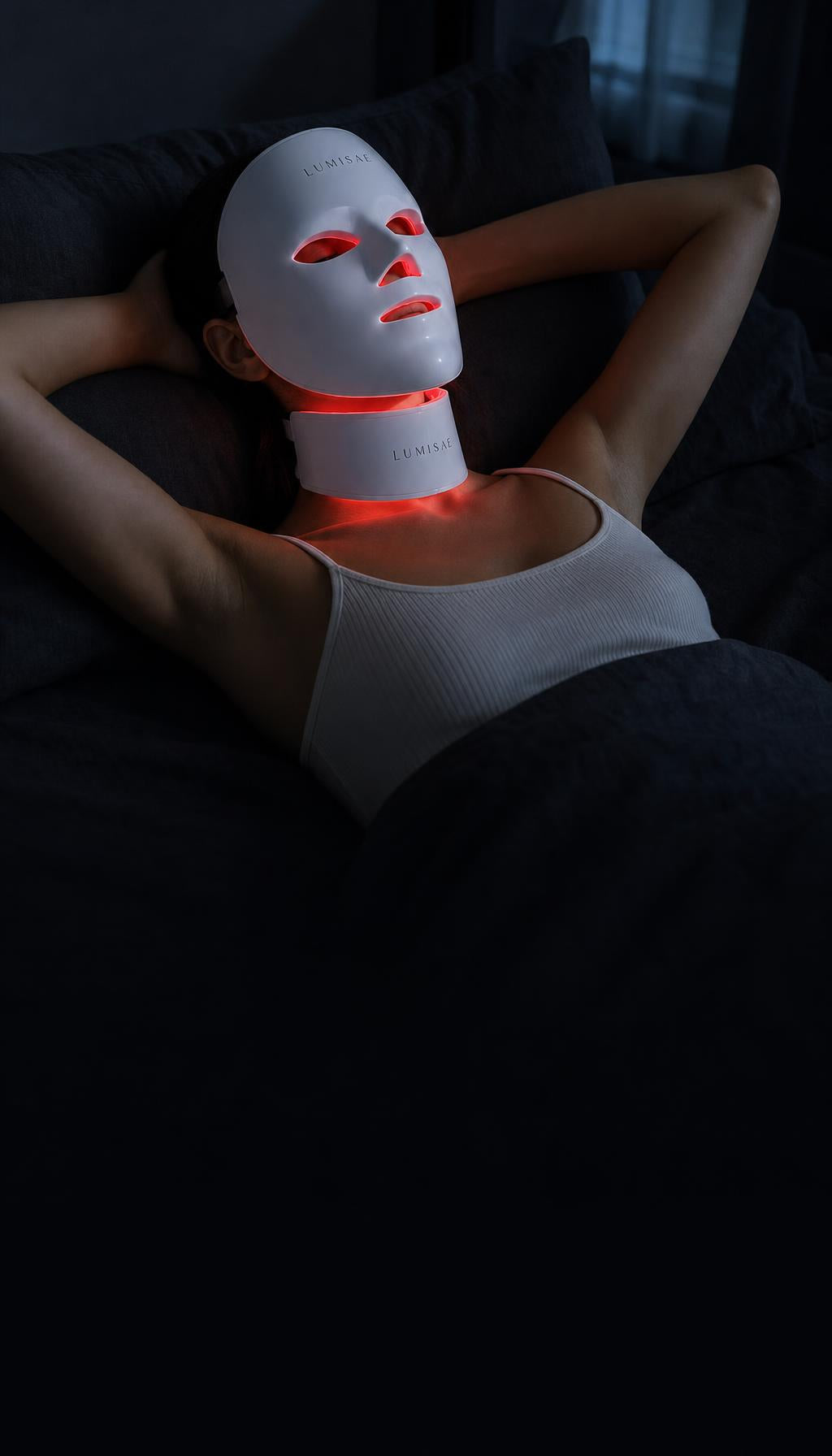Woman resting in bed at night wearing the Lumisae LED mask and neck piece