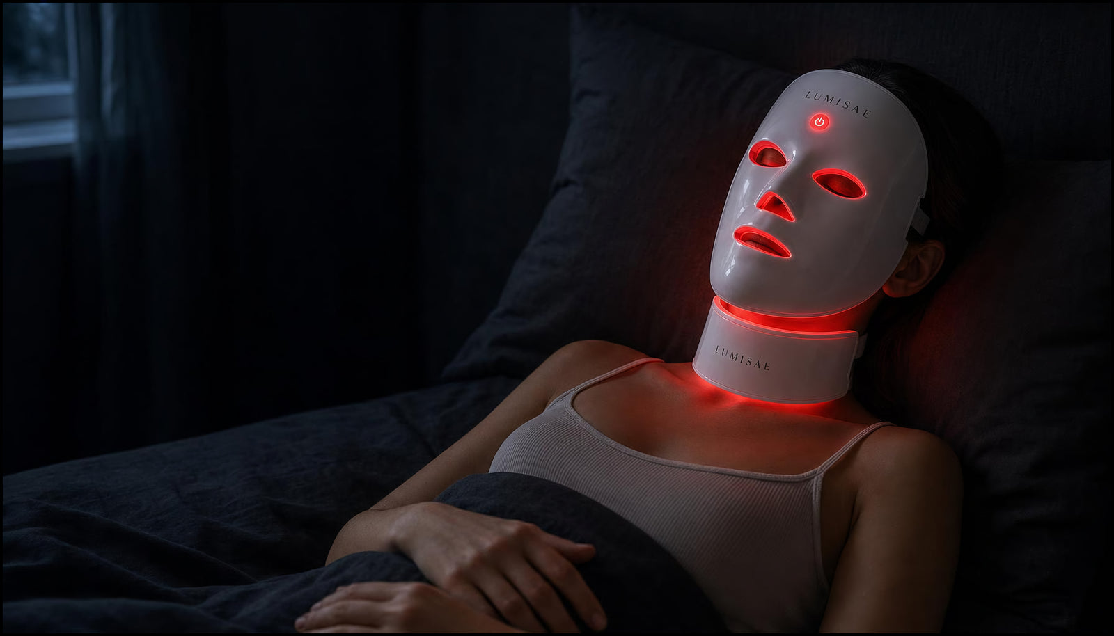Woman resting in bed at night wearing the Lumisae LED mask and neck piece